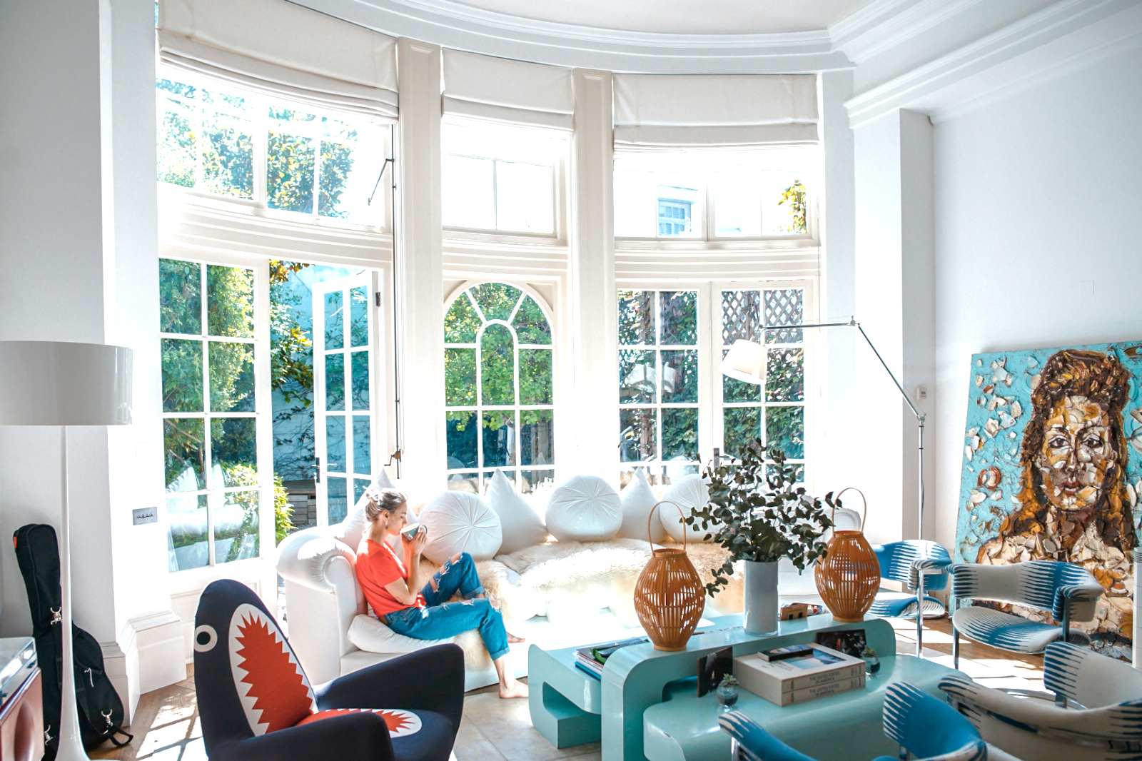 A bright living room with tall windows and colorful paintings, HDR version