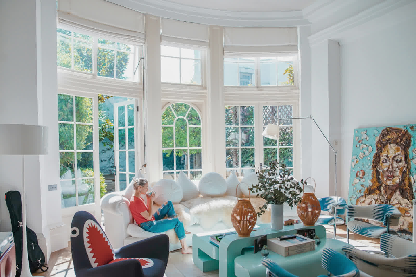 A bright living room with tall windows and colorful paintings, standard dynamic range version